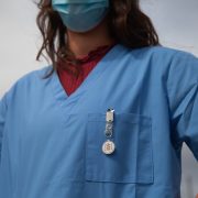 A woman medic wearing blue scrubs and a face mask .
