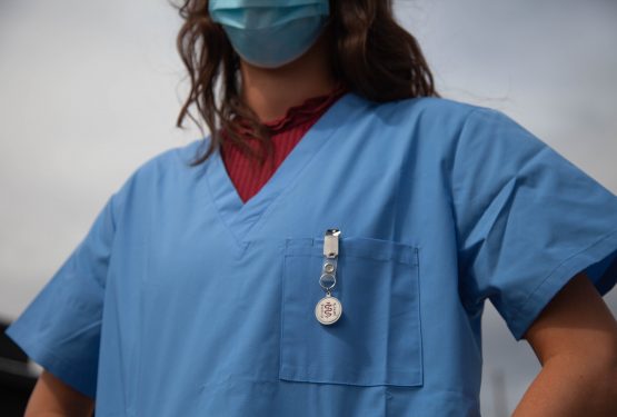 A woman medic wearing blue scrubs and a face mask .